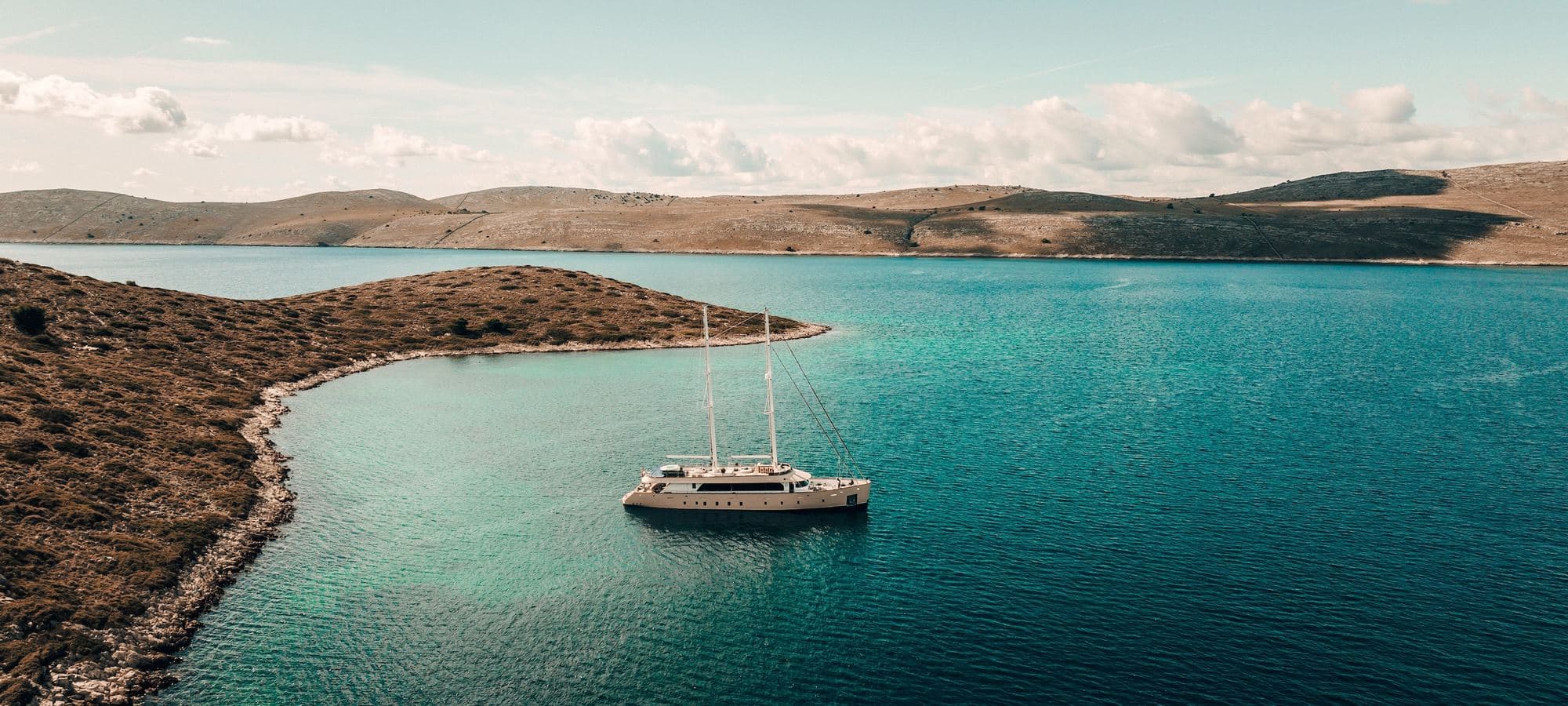 A private sailing yacht at anchor in a turquoise cove